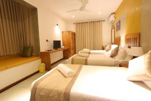 a hotel room with two beds and a television at Lotus Lake Residence in Kandy