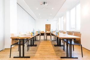 a long dining room with wooden tables and chairs at RiKu HOTEL Neu-Ulm in Neu-Ulm