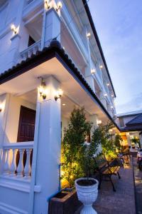a white house with a porch with lights on it at The Lion King Hotel Udonthani in Udon Thani