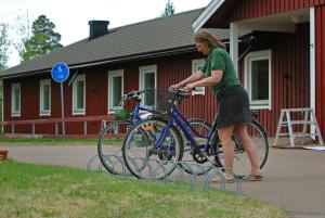 a woman is putting a bike in a bike rack at STF Orsa Hostel in Orsa +36 photos