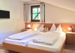 a bedroom with a bed with white sheets and a window at Oberlinderhof in Cadipietra