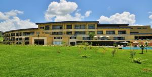a large building with a grass field in front of it at EPIC Hotel & Suites in Nyagatare