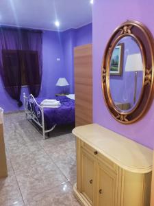 a purple bedroom with a bed and a mirror at Le colline in Capena
