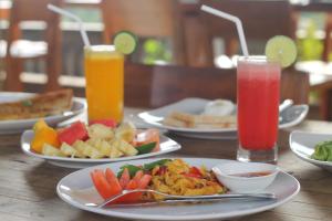 una mesa con platos de comida y dos vasos de zumo en Hibiscus Cottages, en Ubud 78 fotos más
