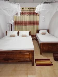 two beds with white sheets in a room at BAS Balcony in Anuradhapura