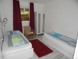 1 dormitorio con 2 camas, silla y ventana en Ferienwohnung Zur Egge, en Bad Driburg