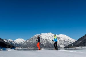 two people on skis in front of a mountain at Liebes Caroline 4-Sterne-Hotel in Pertisau
