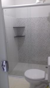 a white bathroom with a toilet and a shower at Suíte Triplex in Capitólio