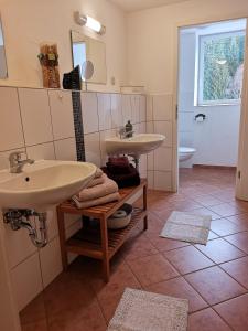 a bathroom with two sinks on a tiled floor at Waldgasthaus & Pension Teichhaus in Holzhau