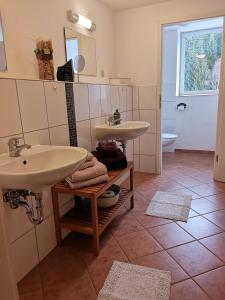ein Bad mit 2 Waschbecken auf einem Fliesenboden in der Unterkunft Waldgasthaus & Pension Teichhaus in Holzhau