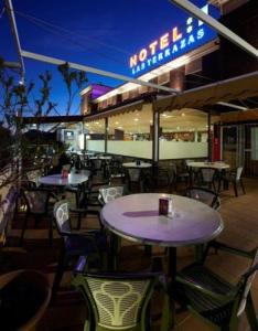 ein Restaurant mit Tischen und Stühlen und einem Neonschild in der Unterkunft Hotel Las Terrazas in Albolote