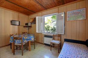 a room with a table and a bed and a window at Villaggio Camping Valdeiva in Deiva Marina