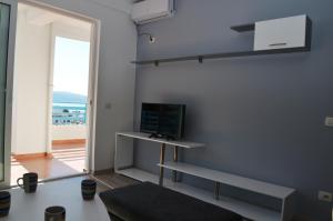 sala de estar con escritorio y TV en la pared en Celin Apartment, en Sarandë