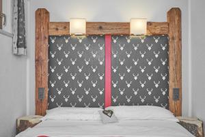 a bed with a black and white headboard with two lights at Apartment Ötztal in Tumpen