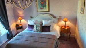 a bedroom with a bed with pillows and two lamps at Hotel Relais Du Postillon in Antibes