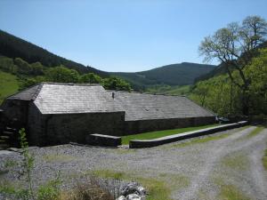 an old barn on a hill with a dirt road at Plasglasgwm in Betws-y-coed