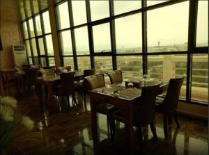 a restaurant with tables and chairs and a large window at Casablanca Hotel in Dar el Beïda