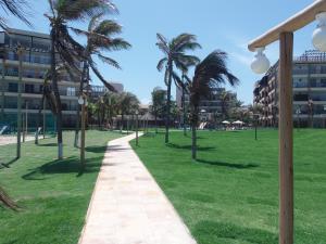 a path in a park with palm trees and buildings at Conforto e Lazer na Frente do Mar ao Lado do Beach Park in Aquiraz