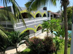 a white house with trees and a swimming pool at Villa tuffah in Watamu