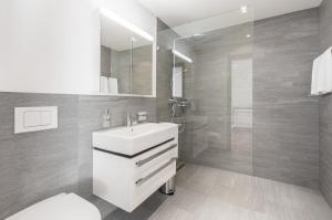 La salle de bains est pourvue d'un lavabo blanc et d'une douche. dans l'établissement LAAX Homes - Taviarna Laax 4,5, à Laax