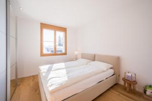 ein weißes Bett in einem Zimmer mit Fenster in der Unterkunft LAAX Homes - Taviarna Laax 2,14 in Laax