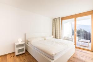 ein weißes Schlafzimmer mit einem Bett und einem Balkon in der Unterkunft LAAX Homes - Taviarna Laax 4,5 in Laax