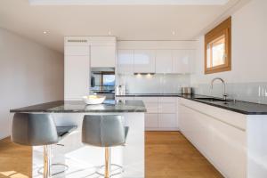 ラアにあるLAAX Homes - Taviarna Laax 2,14のキッチン(白いキャビネット、黒いカウンタートップ付)