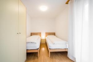 ラアにあるLAAX Homes - Val Mulin 8,2 - Scarpazzaの白い壁とウッドフロアの客室で、ベッド2台が備わります。