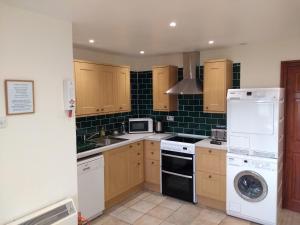 a kitchen with wooden cabinets and a washer and dryer at Llinos Cottage in Beaumaris