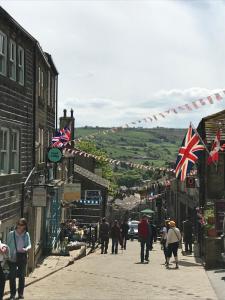 a group of people walking down a street with british flags at Mulberry Cottage with Wood Burner, Garden and Easy Parking in Haworth