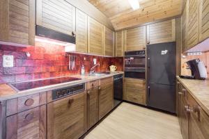uma cozinha com armários de madeira e um frigorífico preto em LAAX Homes - Val Signina 8-17 em Laax