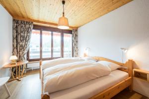 a bedroom with a large bed with a window at LAAX Homes - Val Signina 8-17 in Laax