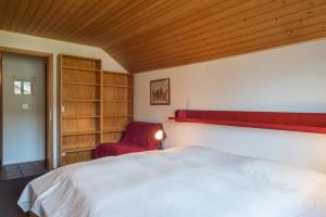 a bedroom with a bed and a red chair at LAAX Homes - Val Signina 8-18 in Laax