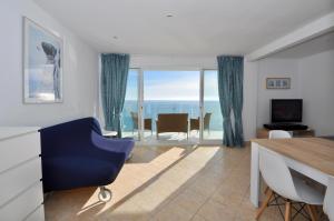 a living room with a blue chair and a table at Vista panorámica in Lloret de Mar
