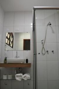 uma casa de banho com um lavatório e um chuveiro com um espelho. em Pousada Três Coqueiros em Praia do Bananal