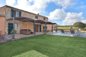 a house with a patio with chairs and a lawn at Finca Maria in Manacor