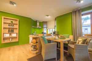オーベルストドルフにあるApartment Alpenwieseの緑の壁のキッチン(木製のテーブルと椅子付)