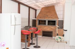 a kitchen with a brick oven and red stools at Residencial Larissa Elena in Florianópolis