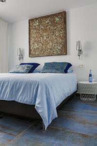 a bedroom with a bed with blue sheets and a painting on the wall at Apartamento Azure- Tierra y Mar in Arrecife