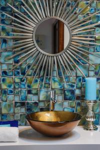 a bathroom sink with a mirror on a mosaic wall at Apartamento Azure- Tierra y Mar in Arrecife