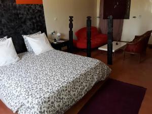 a bedroom with a bed and a red chair at Le ZaNaLi Hotel in Ouagadougou