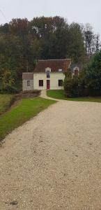 a white house with a red door on a dirt road at La Graine de Beurre proche zoo de Beauval in Seigy
