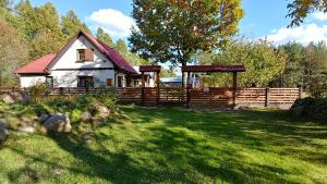 una casa en un patio con una valla de madera en Ranczo w lesie - domki z jacuzzi en Ożarów