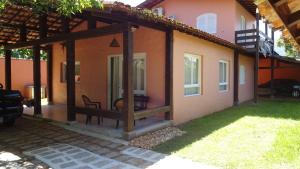 Casa Perequê 100 metros da praia في إلهابيلا: منزل به شرفة وكرسي بالخارج