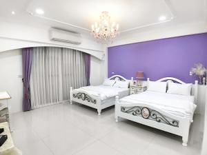 2 camas num quarto com uma parede roxa em Lovi Time B&B em Donggang