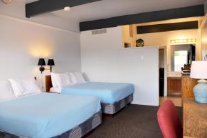 um quarto de hotel com duas camas e uma cadeira vermelha em The Oakwood Inn em Sterling