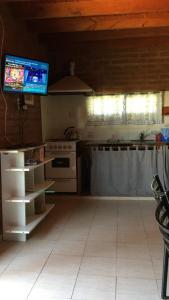 cocina con fogones y TV en la pared en Cabañas Rosarito en Villa Larca