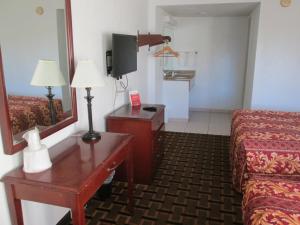 a hotel room with a bed and a table and a mirror at Budget Inn in Cocoa