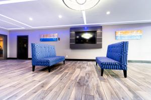 two blue chairs in a room with a tv at SureStay Plus Hotel by Best Western Point Richmond in Richmond