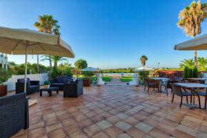 a patio with tables and chairs and umbrellas at Colina Verde Resort in Moncarapacho